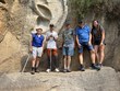 Na fotografii zleva: p. Ing. Tomek, p. Spáčil, p. Ing. Beránek, p. Jakubík, sl. Bc. Lacková – pózující před obřím reliéfem lidského ucha vytesaným do pískovcové skály. Reliéf je obklopen skalní stěnou a lesní zelení