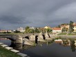 Kamenný most v Písku při pohledu z břehu. Pod mostem je řeka Otava a v pozadí historické domy